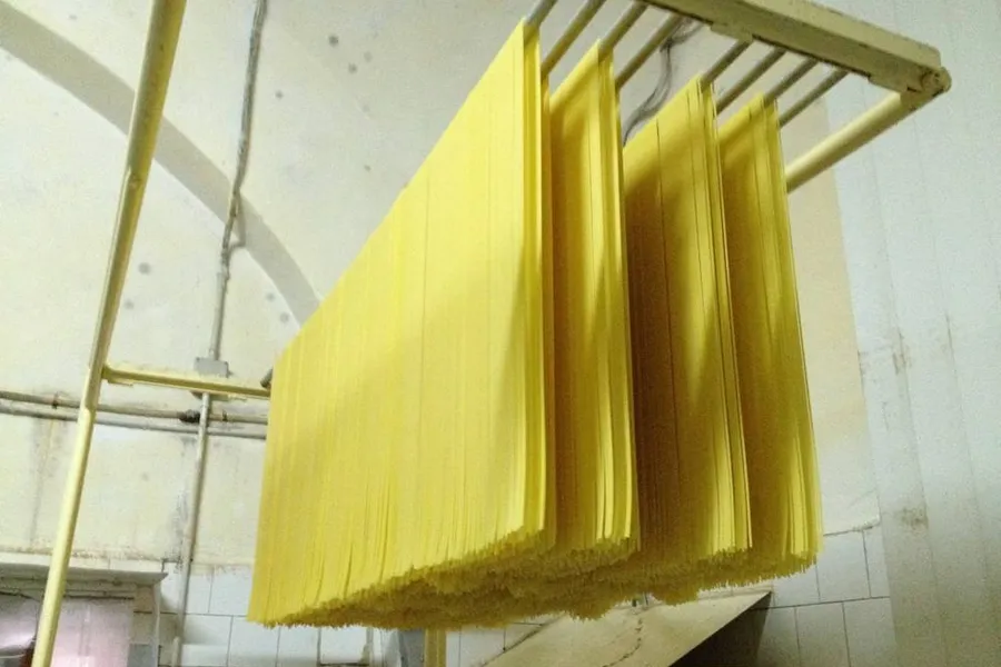 Lunghi spaghetti stesi su canne ad asciugare in un pastificio