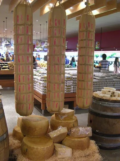 Tre provoloni appesi e una punta di parmigiano su un letto di paglia