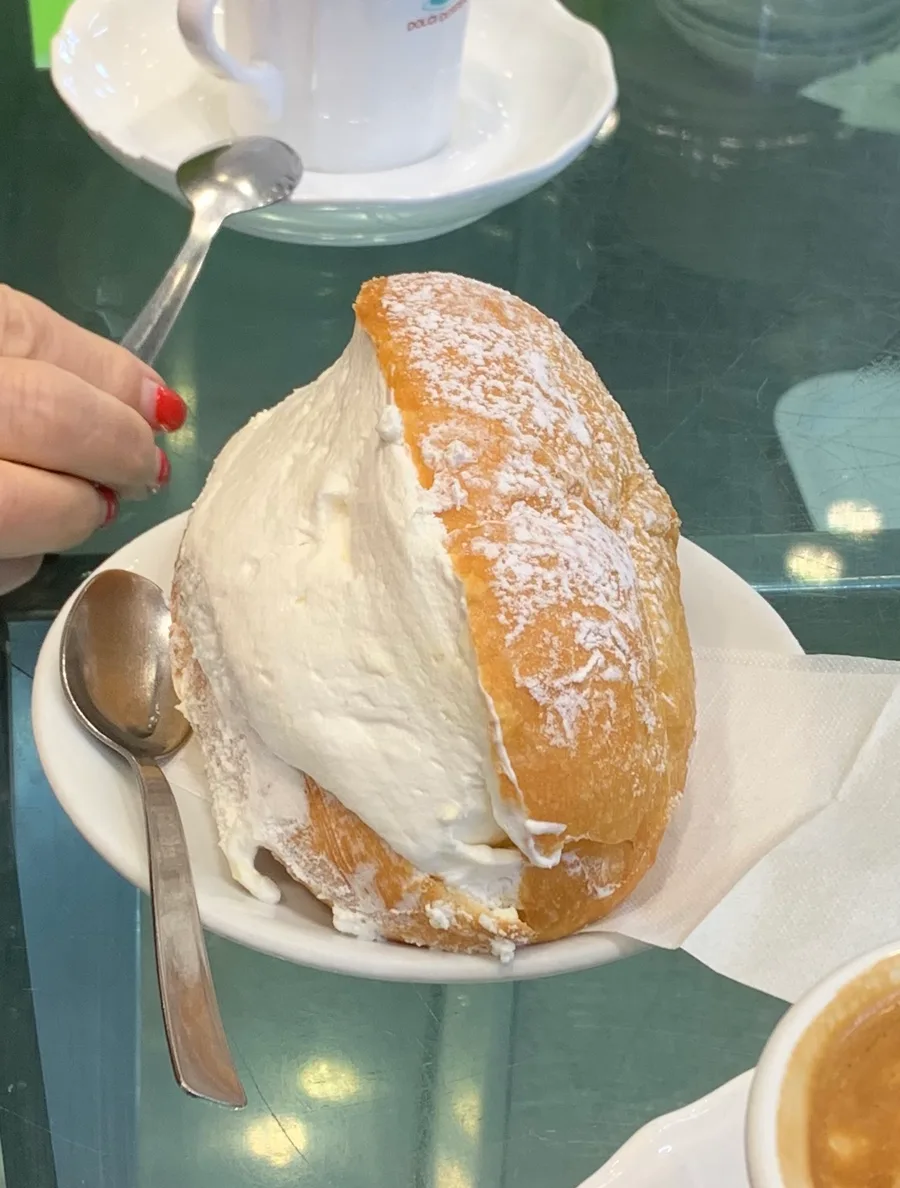 Maritozzo appena sfornato con la panna montata livellata, servito in un bar di Roma