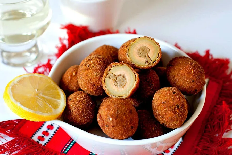 Olive all'ascolana fritte in una ciotola, una aperta a mostrare il ripieno di carne