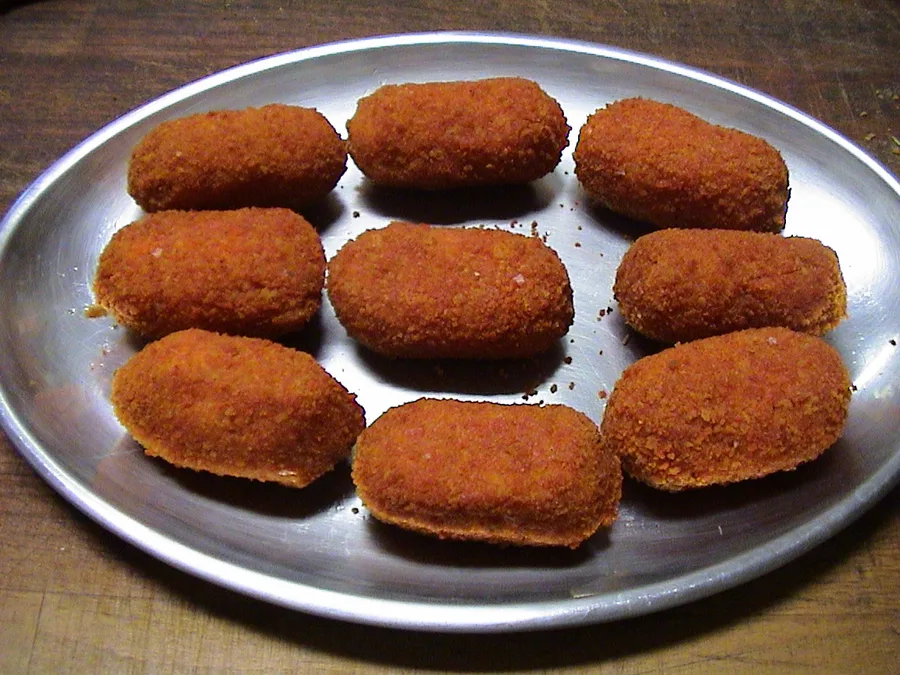 Supplì fritti allineati su un piatto, dorati e di forma allungata
